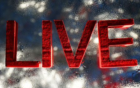 Live inscription with red letters on a wet lightened glassの写真素材