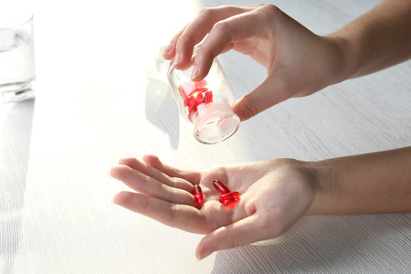 Transparent red pills in female handsの写真素材