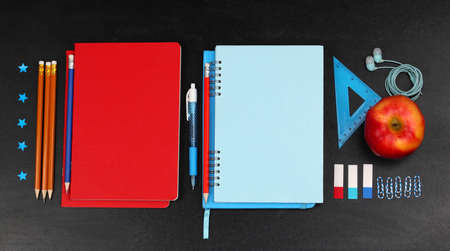 School supplies near blackboard, close up