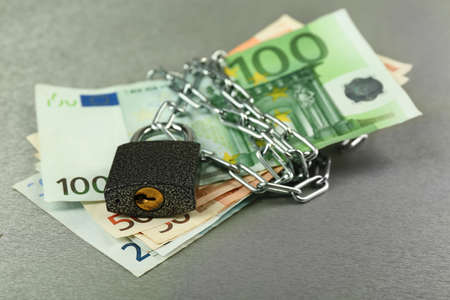 Euro banknotes with lock and chain on gray backgroundの写真素材