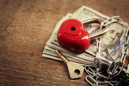 Dollars currency with lock and chain on wooden backgroundの写真素材
