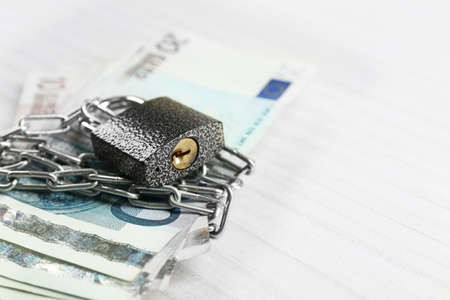 Euro banknotes with lock and chain on wooden table backgroundの写真素材