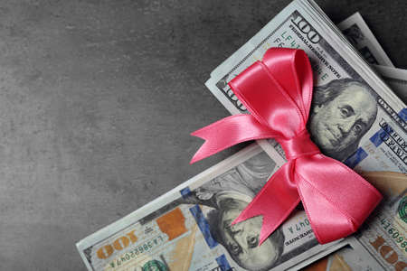 Dollars and colorful bow on grey backgroundの写真素材
