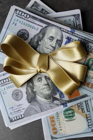 Dollars and colorful bow on grey backgroundの写真素材
