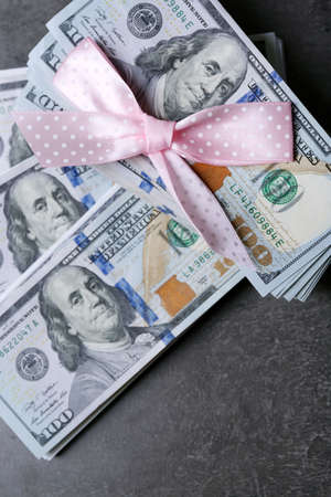 Dollars and colorful bow on grey background