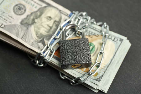 Dollars currency with lock and chain on grey background