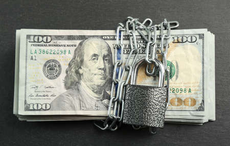 Dollars currency with lock and chain on grey background