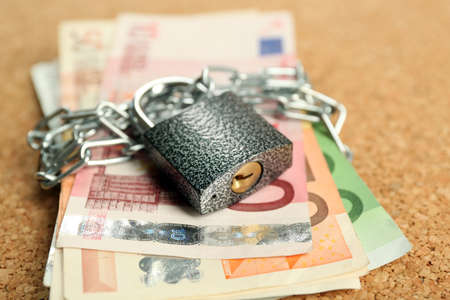 Euro banknotes with lock and chain on wooden background