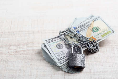 Dollars currency with lock and chain on wooden table backgroundの写真素材