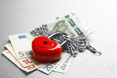 Euro banknotes with lock and chain on gray background
