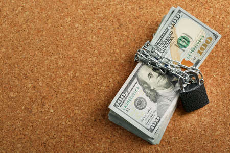 Dollars currency with lock and chain on wooden background