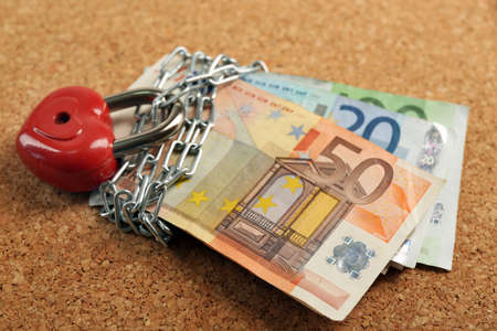 Euro banknotes with lock and chain on wooden backgroundの写真素材