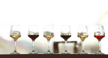Many glasses of different wine in a row on a tableの写真素材