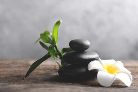 Spa stones with bamboo and tropical flower on wooden table against grey backgroundの写真素材