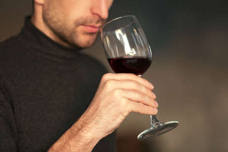 Man sniffing red wine in a glass, close upの写真素材