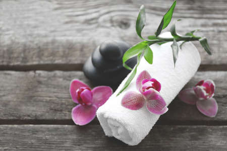Spa stones with towel, bamboo and purple orchids on wooden backgroundの写真素材