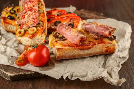 Hot pizza baguette with bacon and cheese on wooden tableの写真素材