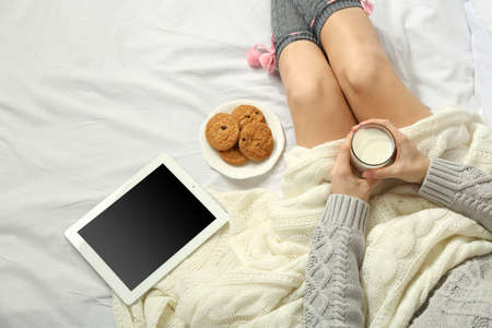 Woman with tablet drinking milk on her bedの写真素材