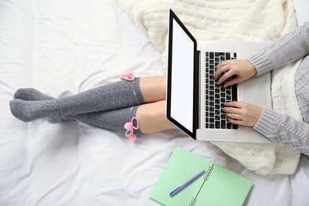 Woman using laptop on her bed