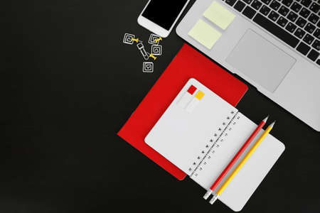Workplace with mobile phone, laptop and stationery on black table