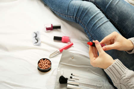 Woman applying makeup on her bedの写真素材
