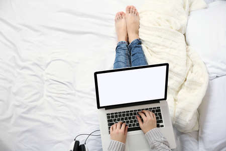 Woman using laptop on her bedの写真素材