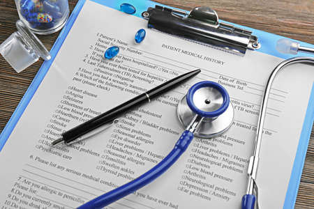 Medical stethoscope, clipboard, pills and pen on the tableの写真素材