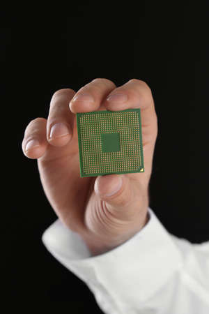 Male hand holding microprocessor on black background