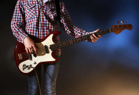 Young man playing electric guitar on lighted foggy backgroundの写真素材