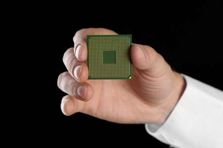 Male hand holding microprocessor on black background