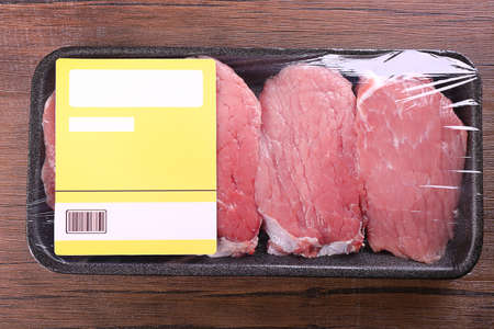 Packed pieces of beef meat on wooden background