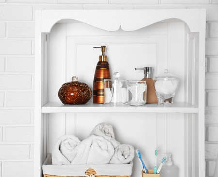Bathroom set with towels, toothbrushes and sponge on a shelf in light interiorの写真素材