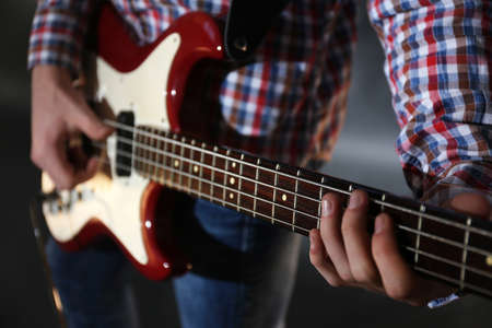 Young man playing electric guitar on lighted foggy background