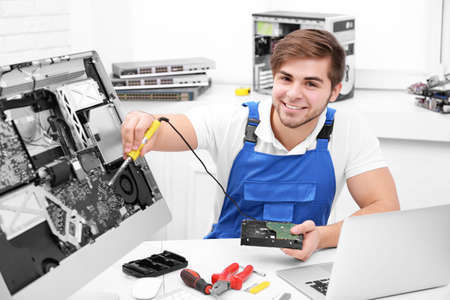 Young repairer working with soldering iron in service center