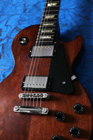 Brown electric guitar on blue wooden background