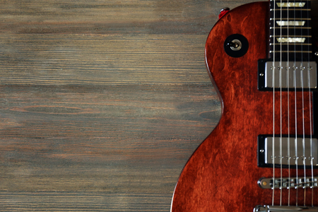 Brown electric guitar on wooden backgroundの写真素材