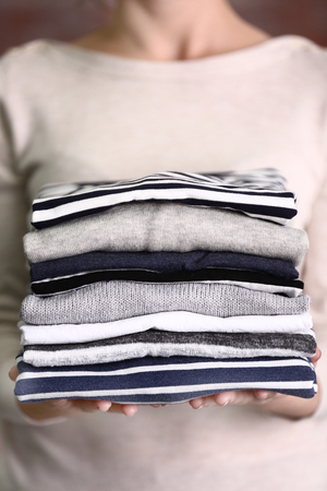 Woman holding washed and dried clothes on brick wall backgroundの写真素材