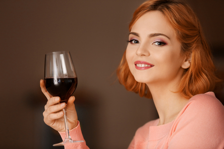 Young woman with glass of red wine on blurred backgroundの写真素材