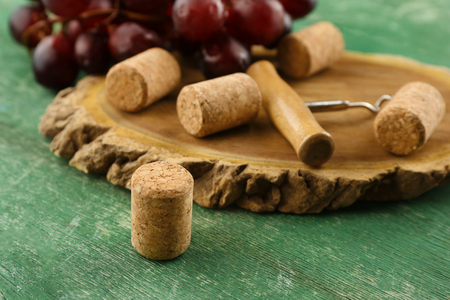 Wine corks and tailspin with bunch of grapes on wooden backgroundの写真素材