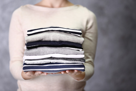 Woman holding washed and dried clothes on grey background