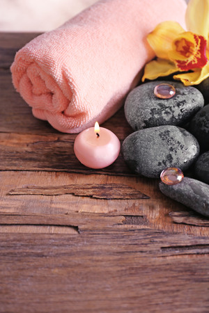 Spa still life with stones, towel, flower and candlelight on wooden backgroundの写真素材