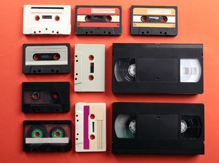 Set of old audio and video cassettes on red background