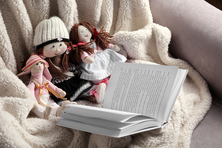 Rag dolls with fairy tales book on bedspread. Childhood conceptの写真素材