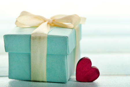 Gift box and decorative hearts on color wooden table, on light backgroundの写真素材