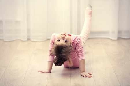 Little cute girl in pink leotard making new ballet movement at dance studioの写真素材