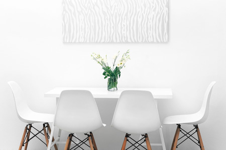 Modern dining room. White chairs and table with bouquet of flowers, abstract picture on the wallの写真素材