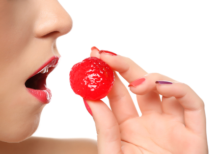 Beautiful girl with colorful manicure and red candy, isolated on whiteの写真素材