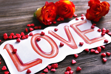 Valentine's Day concept. Painted word LOVE and roses on wooden background, close upの写真素材