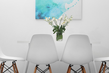 Modern dining room. White chairs and table with bouquet of flowers, abstract picture on the wallの写真素材