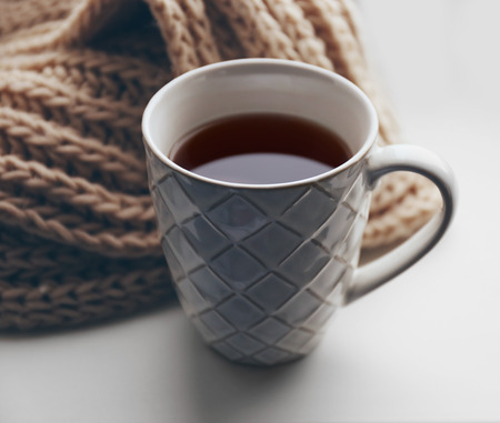Cup of tea and warm knitted scarf on windowsill, close upの写真素材